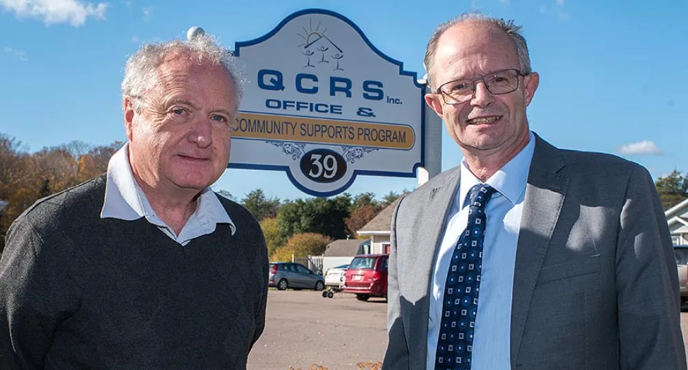 Two people standing in front of a sign