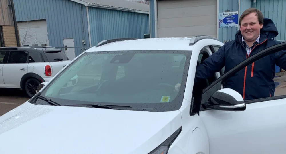 image of a person standing inside the open front door of a white car