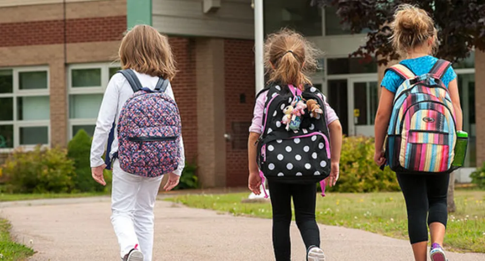 three children walking toward a school