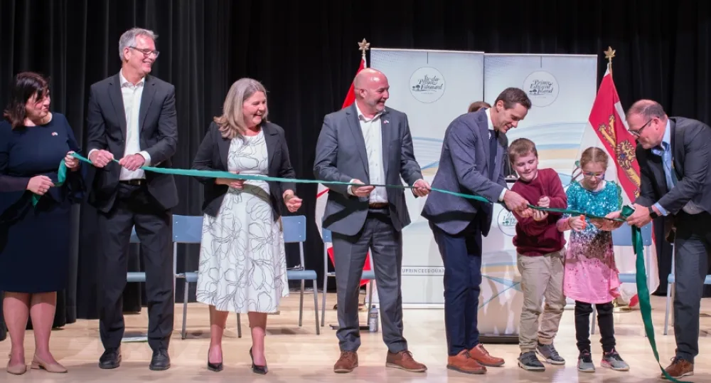 People standing in a line on stage cutting a ribbon