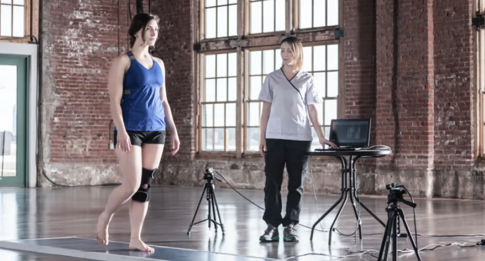 Woman is walking on a mat that measures her foot pressure points, while another woman looks on