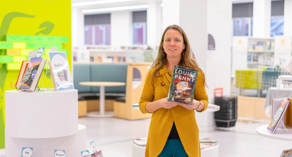 Top library picks for 2023 image of a person standing in a library holding a book in front of her
