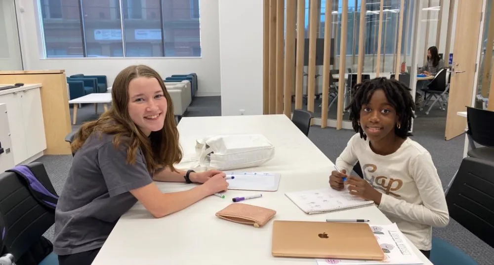 Tutor and young child sit together at a table