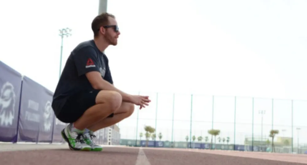 Image of a person stretching near a running track