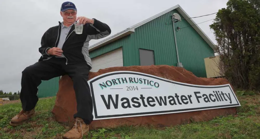Les Standen holds a clear glass of Rustico&#039;s treated wastewater