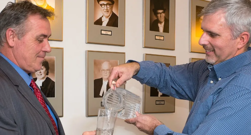 Photo shows Environmental Advisory Council Chair Dean Stewart pouring a glass of water for Communities, Land and Environment Minister Robert Mitchell and 