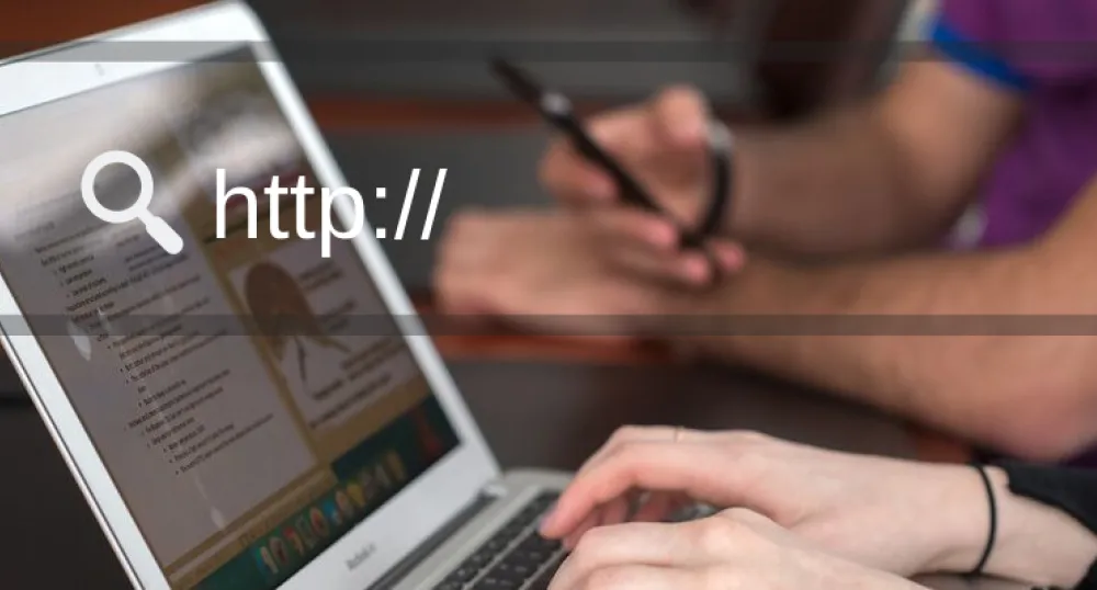 Image of individual using a laptop with text that reads &quot;http://...&quot;