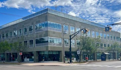 Exterior view of a building.  A cross walk and bus shelter are visible.