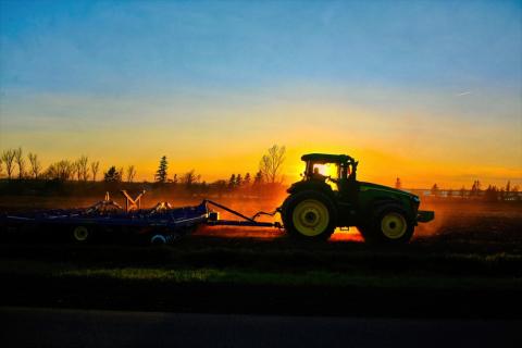 Tractor cultivating a field at sunset
