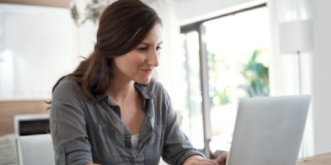 Woman smiling while working on her laptop at home.