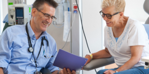 Doctor and smiling patient discussing documents in a medical setting.