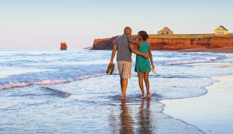 Couple strolls along red sand beach on Prince Edward Island