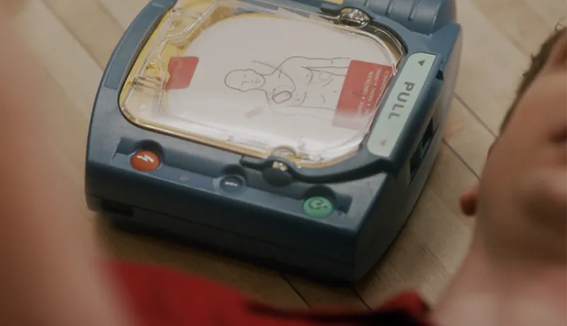 AED sitting on floor next to man.