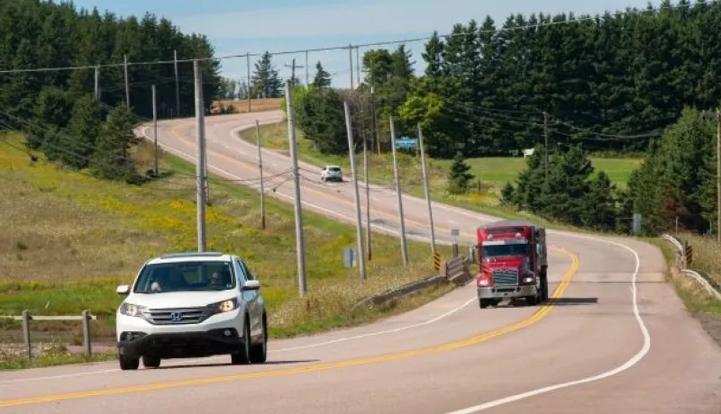 a car and a transport truck driving on a highway in Prince Edward Island