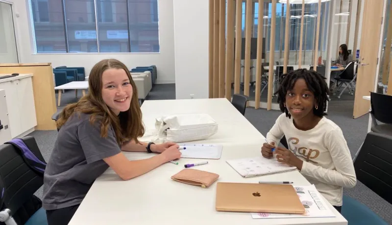Tutor and young child sit together at a table