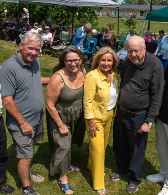 Five people stand together outside during a sunny day.
