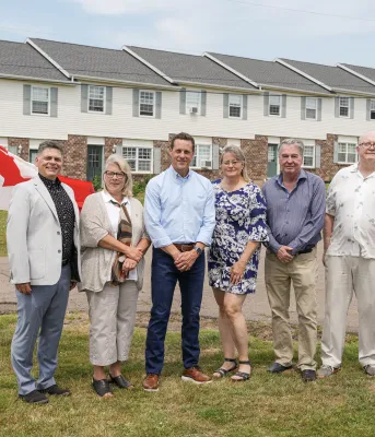 Six people standing in front of housing units 