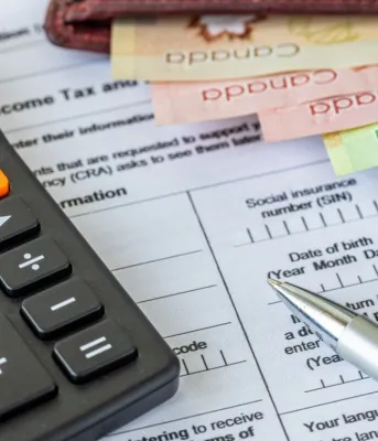 A calculator and colorful Canadian bills sit on a tax document.