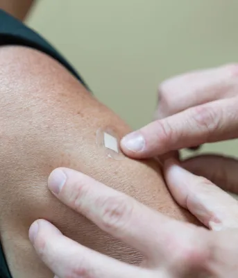 An arm with a small bandage over a recent vaccination site.