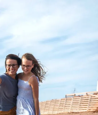 two people taking a photo in front of a lighthouse