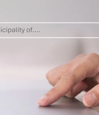 Municipal Directory A person's hand resting on a laptop keyboard, with the screen displaying a search bar reading "municipality of."