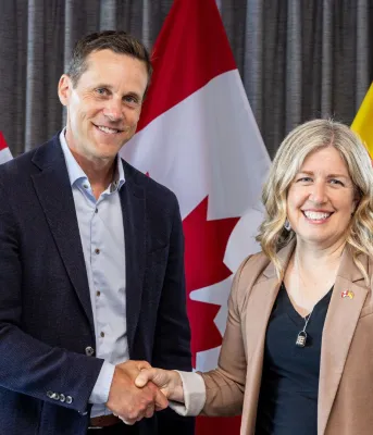 Les Premiers ministre se serrant la main devant les drapeaux de l&#039;Île-du-Prince-Édouard, du Nouveau-Brunswick et du Canada.