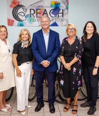 Five people stand in front of a Reach Foundation poster.