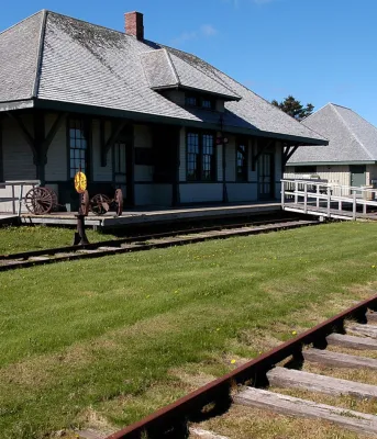 The Elmira train station stands behind train tracks on a sunny, blue-sky day.