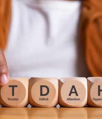 Hands of person spelling TDAH with wooden blocks on a table