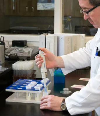 Man wearing white lab coat using laboratory equipment in a lab