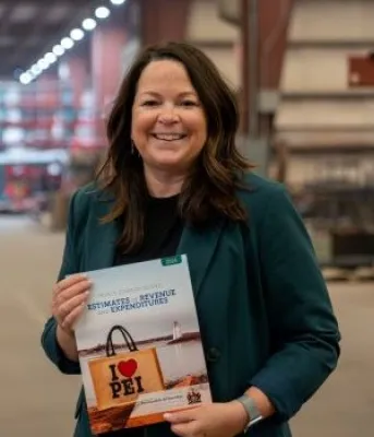 Minister Jill Burridge holding a copy of the 2026-2026 Operating Budget
