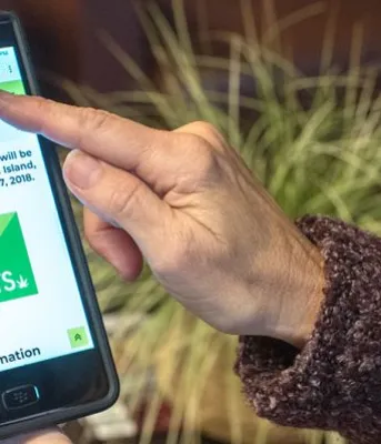 Woman holding mobile photo that is displaying the JUST THE FACTS PEI cannabis website