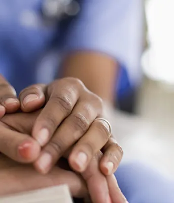 Organ and Tissue Donation A health professional has their two hands on top of a woman’s hands showing comfort.