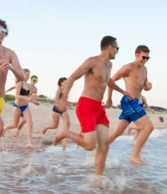 Group of youth run into the water at Basin Head beach