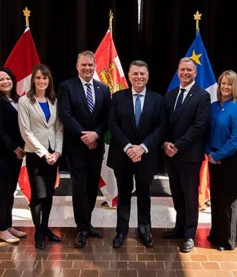 Premier King and new Cabinet members stand in front of PEI and Canada flags