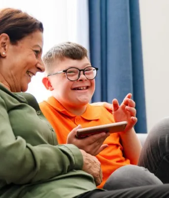 Islanders invited to join community sessions to provide feedback on AccessAbility Supports and Residential Services Programs image of an older person and a younger person sitting on a couch and laughing