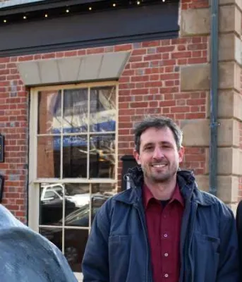 Names of arts grants recipients released Two people sanding beside a Great Blue Heron statue