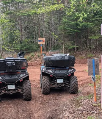 two ATVS parked on a dirt road