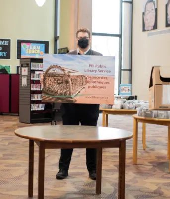 Image of three people in a library holding battery recycling boxes