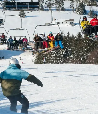Brookvale Alpine Site Winter scene at Brookvale Ski Park, featuring a skier on the hill and the chair lift transporting more skiers