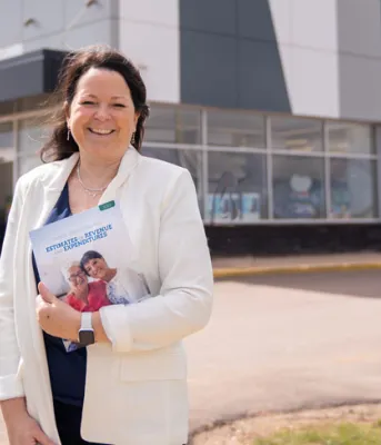 image of a person standing in front of a pharmacy while holding budget document