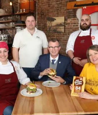 Five people holding hamburgers sitting at a table.