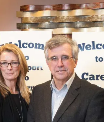 Minister Brown and three other people standing in front of Career Bridges sign and three of them are holding an information brochure.