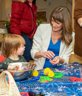 image of  some women sitting at a small table with some young children doing crafts