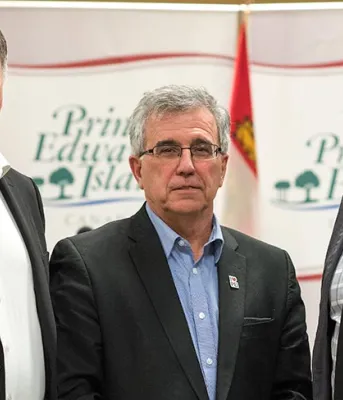 Three people standing shoulder to shoulder in front of provincial banners