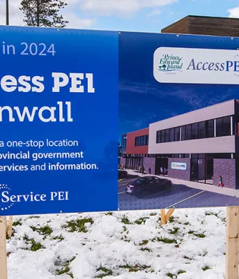 Access PEI adds services for health care assistance, and a new location in Cornwall image of two people standing in front of a 4 by 8 sign announcing upcoming building construction