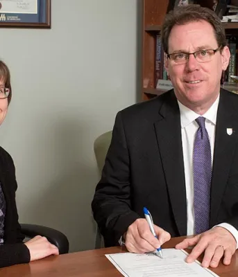 Man and woman side by side sitting behind a desk 