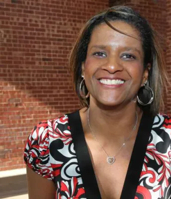 Deborah Langston Deborah Langston stands outdoors in front of a red brick building