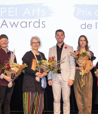 image of a line of people standing on a stage holding bouquets of flowers receiving awards