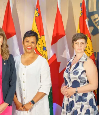 image of  five people standing in ront of some flags and signage